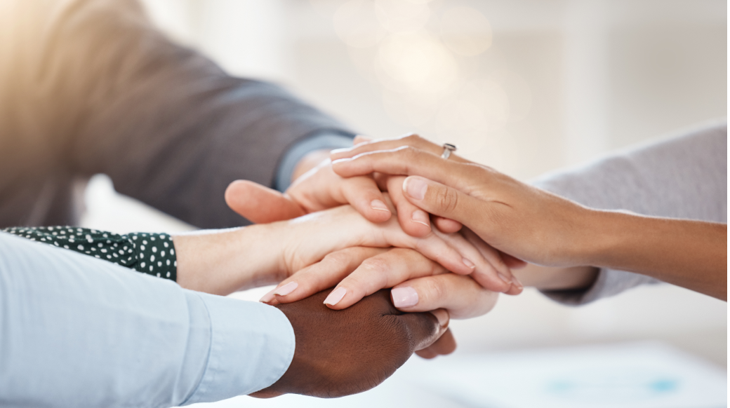 A group of diverse people stacking their hands together, symbolizing trust and unity.
